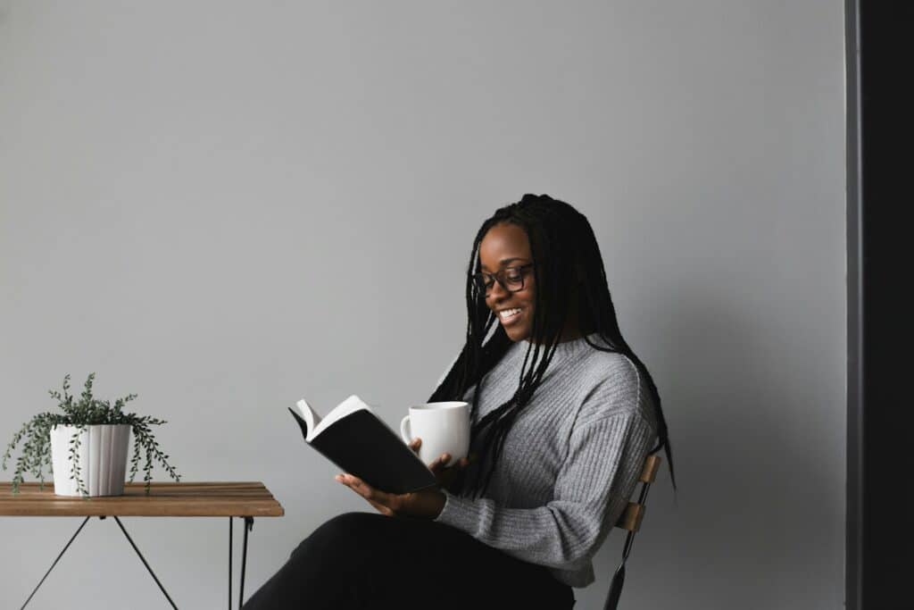 happy woman reading in chair by table