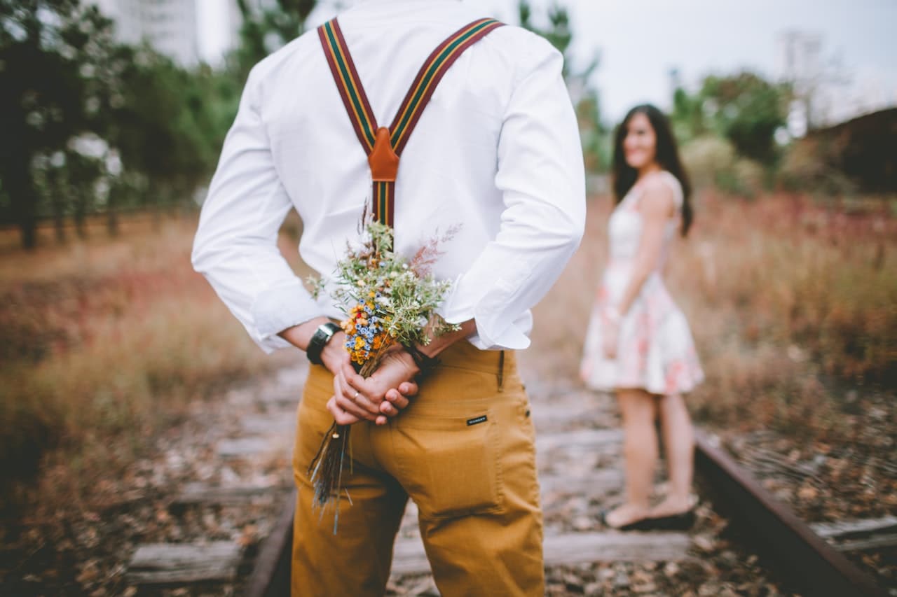 Man hiding flowers behind his back