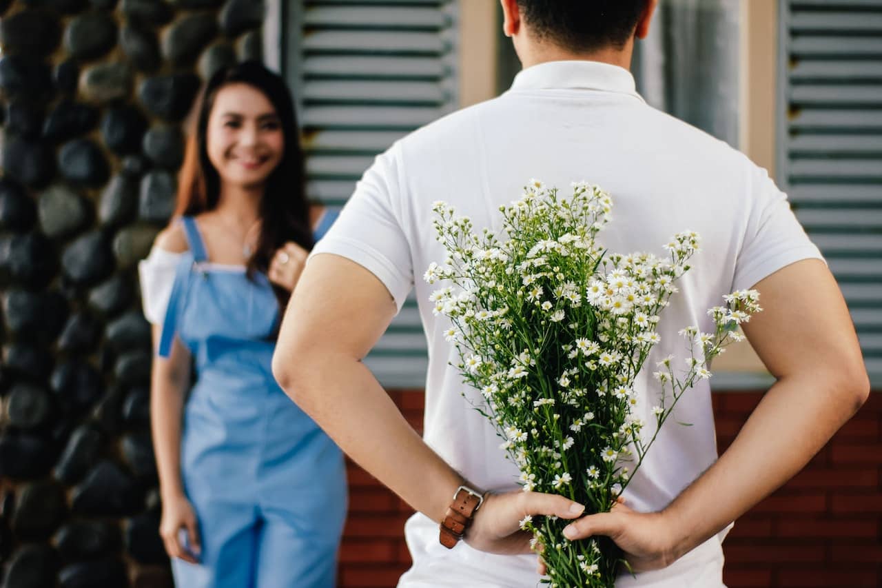 boy surprising girl with flowers